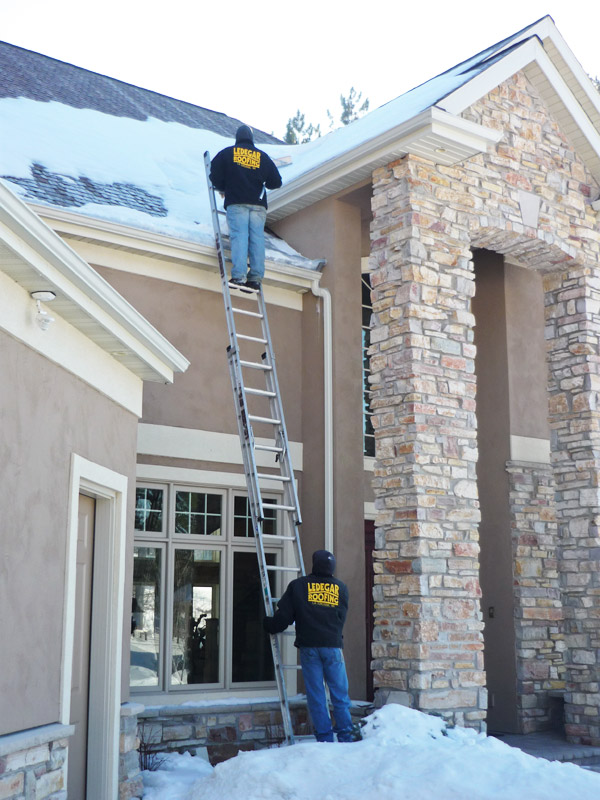 Ledegar Roofing Employees safety removing snow of a residential home.