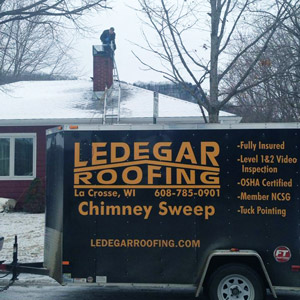 Ledegar Roofing performing a chimney sweep on a residential home.