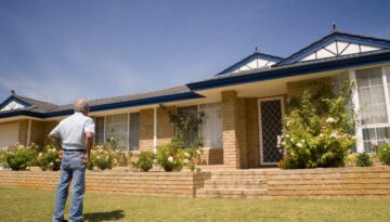 An older man standing outside his home evaluating how to extend the roof life.