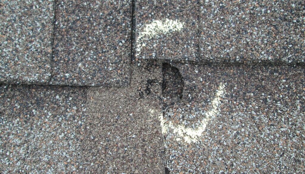 A close-up of a residential roof with hail damage.