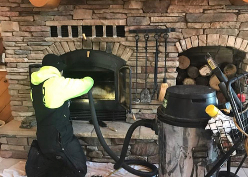 A Ledegar Roofing employee performing a scheduled chimney sweep on a fireplace in a residential home.