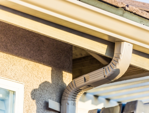 The top curve of a residential home downspout attached to gutters.