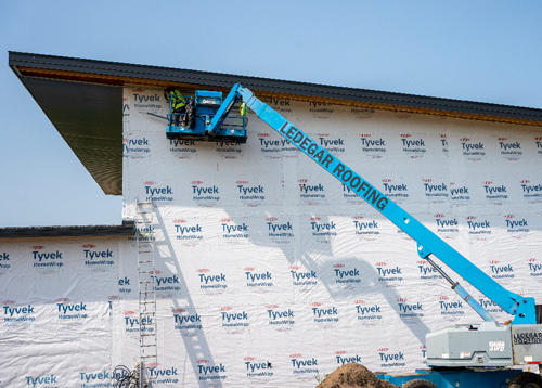 A Ledegar Roofing employee installing new soffit on a newly constructed home in a boom truck bucket.