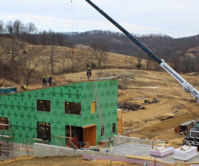 A sheet metal worker operates a forklift crane as Ledegar Roofing employees work to add a roof to a commercial building.