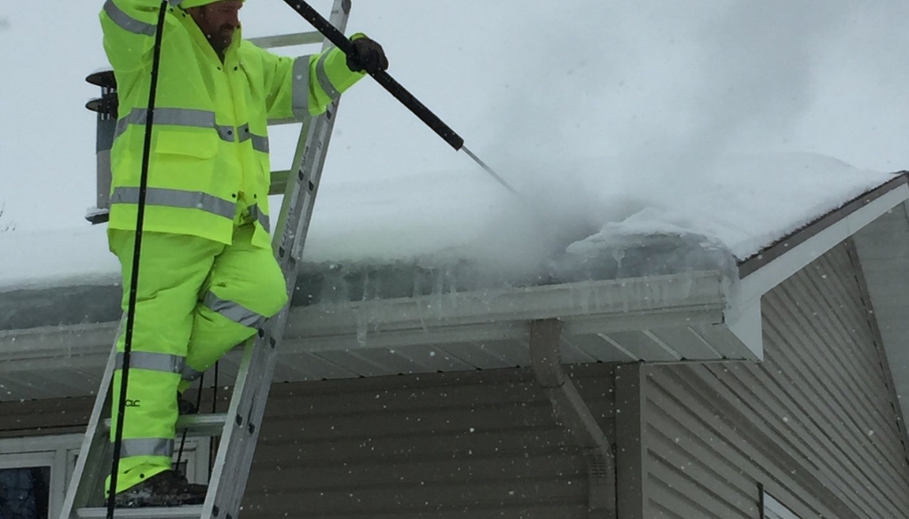 Ledegar Roofing employee removes ice from a roof.