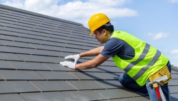 A professional roofer finishing a shingle replacement on a residential home.