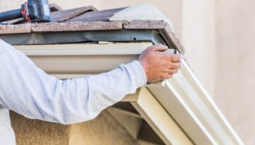 Construction worker placing a gutter on a home.