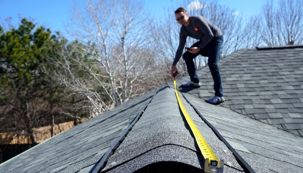 Roofer measuring the top of a roof.