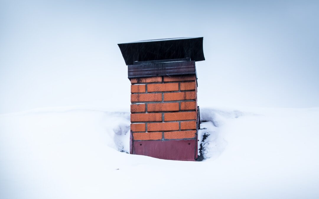 A snow-covered roof with a brick chimney and black chimney cap.
