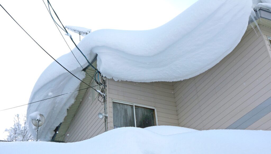 A residential home roof piled high with heavy snow.