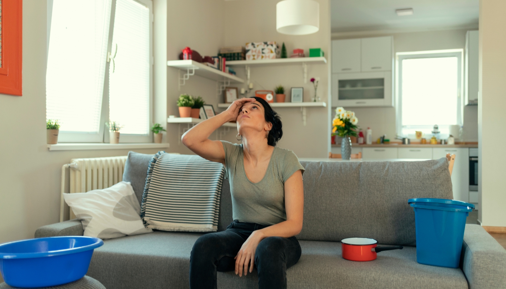 A La Crosse, Wisconsin homeowner staring up at her ceiling assessing the water damage from a roof leak or condensation.