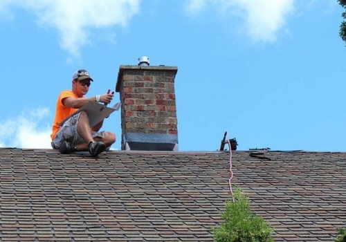 Ledegar Roofing employee completing a chimney inspection on a building in La Crosse, Wisconsin.