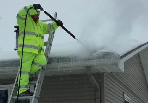 Ledegar Roofing employee removing snow from a residential roof. 