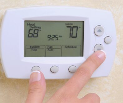 Close-up of someone lowing their thermostat to help reduce their heating bills.