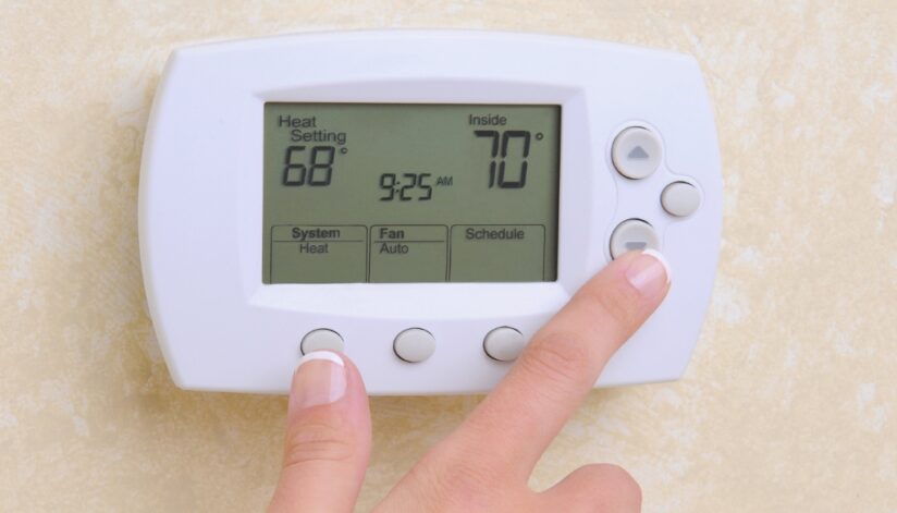 Close-up of someone lowing their thermostat to help reduce their heating bills.