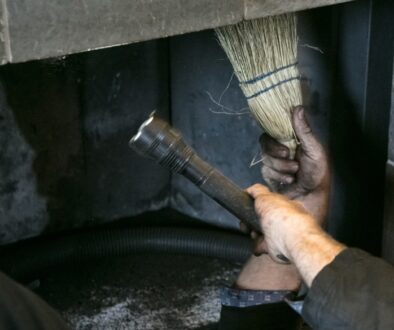 A professional roofer doing a routine chimney cleaning before winter.