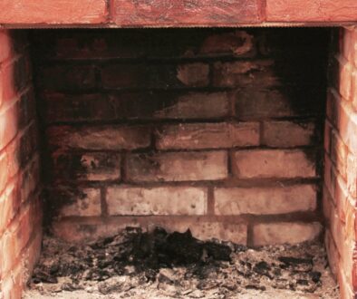 A dirty, red brick fireplace and chimney in need of a professional cleaning.