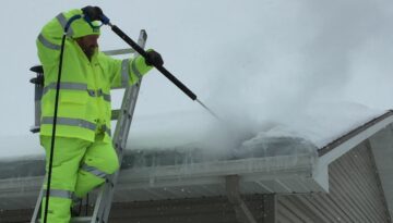 A roofing expert at Ledegar Roofing removing an ice dam from a residential roof.