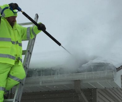 A roofing expert at Ledegar Roofing removing an ice dam from a residential roof.