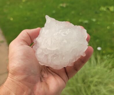 A hand holding a softball-sized piece of hail from a severe storm in West Salem, Wisconsin.