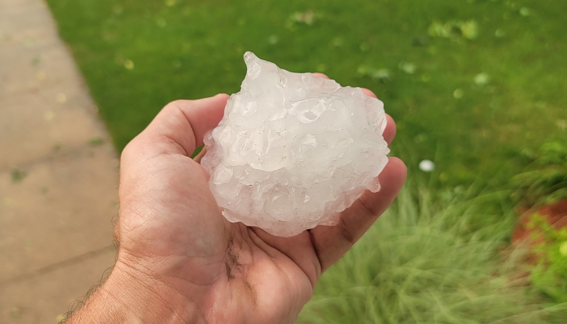 Hail Damage 101: What Homeowners Should Check After A Storm A hand holding a softball-sized piece of hail from a severe storm in West Salem, Wisconsin.