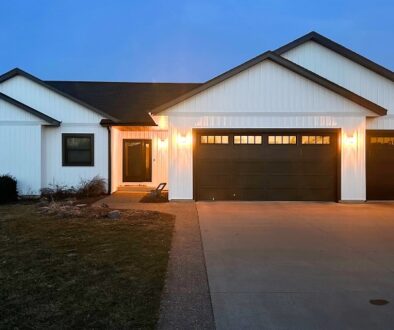 A residential home in West Salem, Wisconsin with new home siding in classic white with black fascia, soffits, and gutters.
