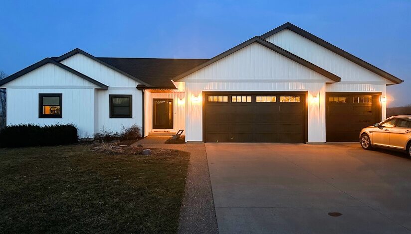 A residential home in West Salem, Wisconsin with new home siding in classic white with black fascia, soffits, and gutters.