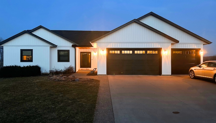 How New Siding Can Boost Energy Efficiency This Summer A residential home in West Salem, Wisconsin with new home siding in classic white with black fascia, soffits, and gutters.