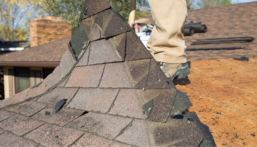 Pulling up asphalt singles on a residential home roof.