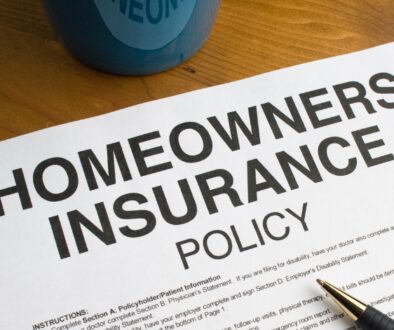 A homeowners insurance policy document on a desk, used to review roof replacement insurance coverage after storm damage.