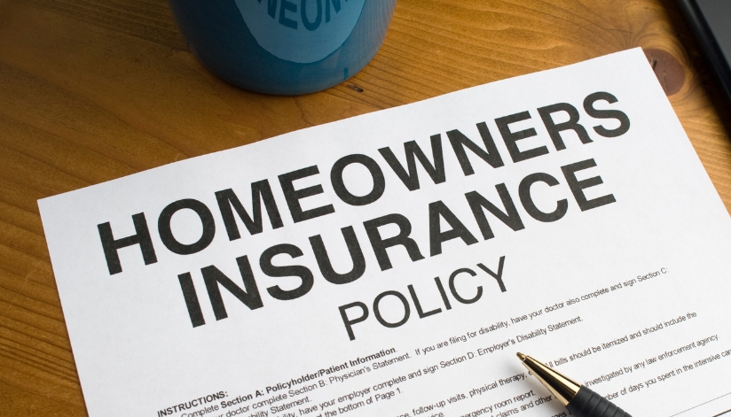 A homeowners insurance policy document on a desk, used to review roof replacement insurance coverage after storm damage.