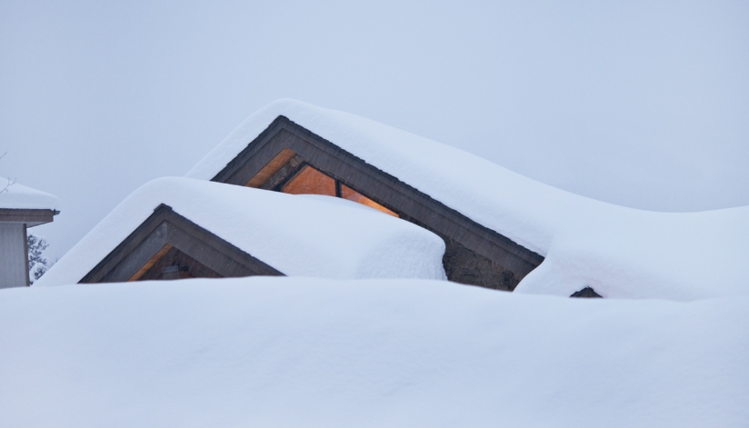 A residential home with thick heavy snow on the roof.