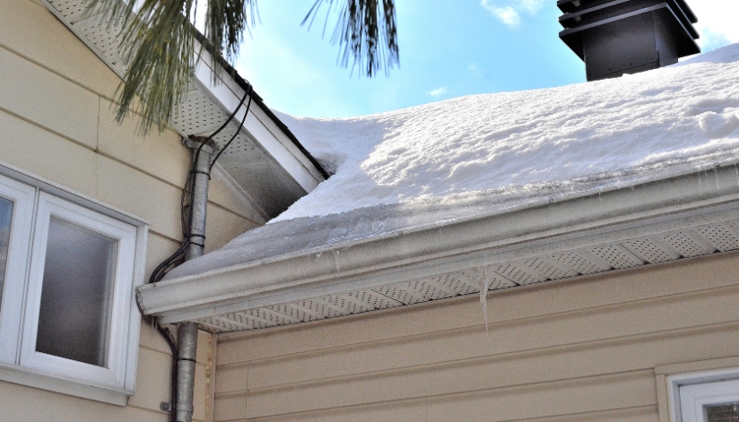 A residential home roof with a severe ice dam on the room and gutters.
