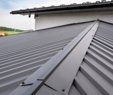 Close-up shot of the peak of a dark gray, metal roof.