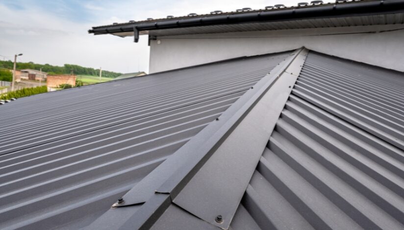 Close-up shot of the peak of a dark gray, metal roof.