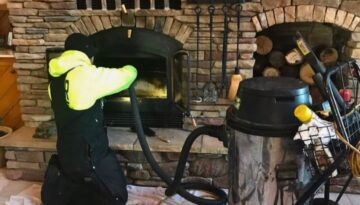 A Ledegar Roofing professional cleaning out a home fireplace and chimney.